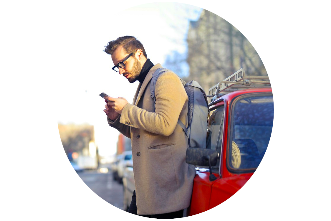 man with phone next to&nbsp;a&nbsp;red car